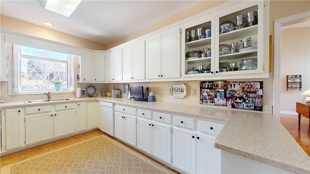 kitchen featuring dishwasher, light hardwood / wood-style floors, kitchen peninsula, sink, and white cabinetry