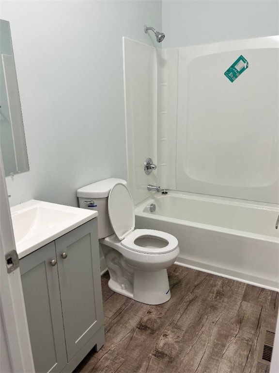 full bathroom with hardwood / wood-style floors,  shower combination, vanity, and toilet