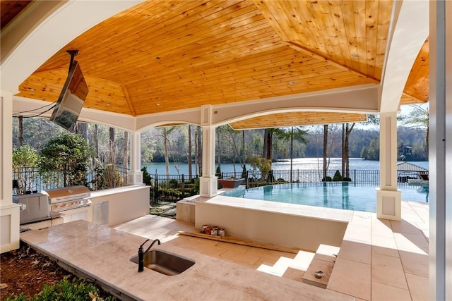 view of patio featuring area for grilling, sink, a gazebo, a water view, and an outdoor kitchen