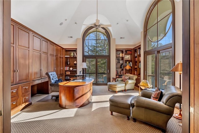 carpeted home office featuring high vaulted ceiling, ceiling fan, built in desk, and wooden walls