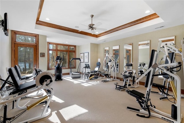 workout area with ceiling fan, a raised ceiling, and carpet flooring