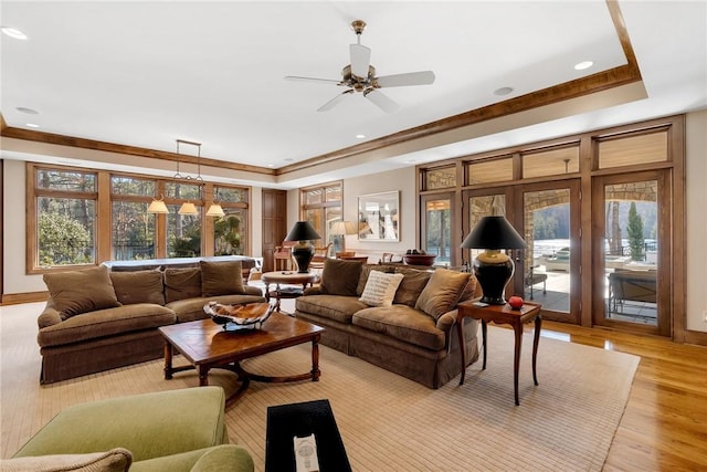 living room featuring ceiling fan, a tray ceiling, light hardwood / wood-style flooring, and crown molding