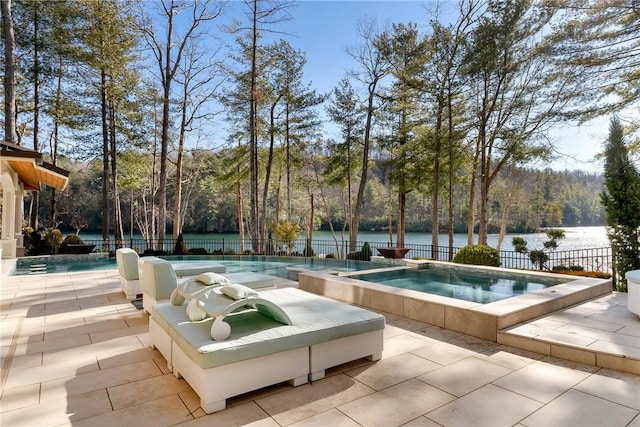 view of pool with an in ground hot tub, a water view, and a patio