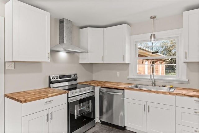 kitchen featuring sink, wooden counters, wall chimney range hood, and stainless steel appliances