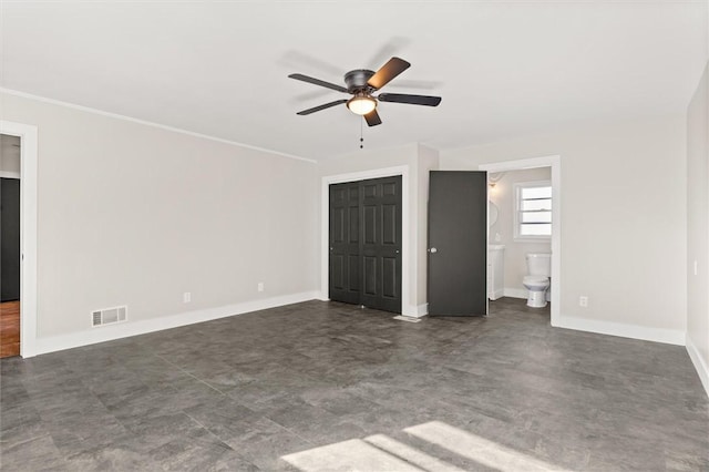 unfurnished bedroom with ceiling fan, ensuite bathroom, and a closet