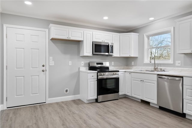 kitchen with sink, crown molding, stainless steel appliances, and white cabinetry