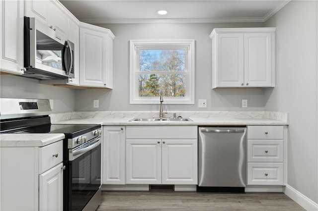 kitchen with white cabinets, sink, stainless steel appliances, and ornamental molding