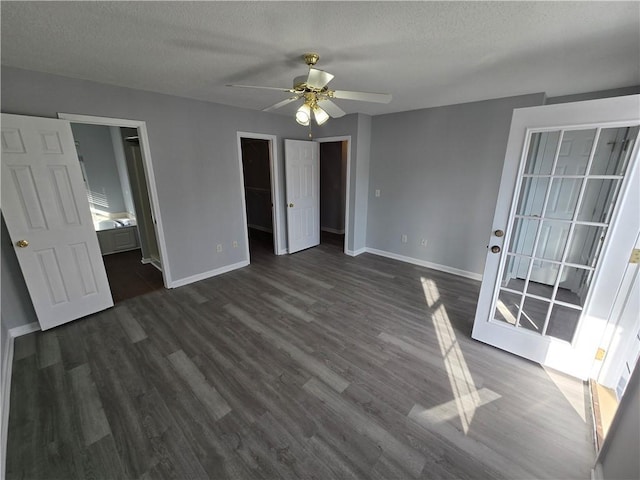 unfurnished bedroom with connected bathroom, ceiling fan, dark hardwood / wood-style floors, a textured ceiling, and a walk in closet