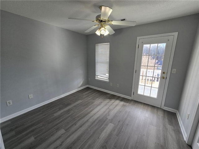 empty room with ceiling fan, dark wood-type flooring, and a textured ceiling