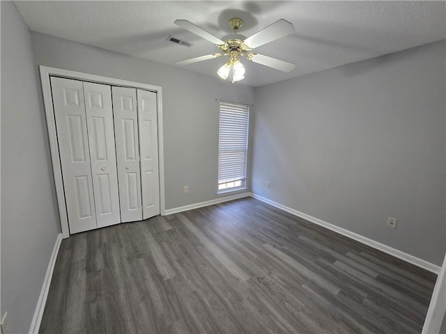 unfurnished bedroom with a closet, ceiling fan, a textured ceiling, and dark wood-type flooring