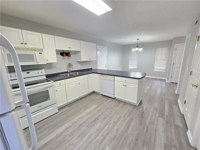 kitchen with white appliances, kitchen peninsula, a notable chandelier, white cabinetry, and sink