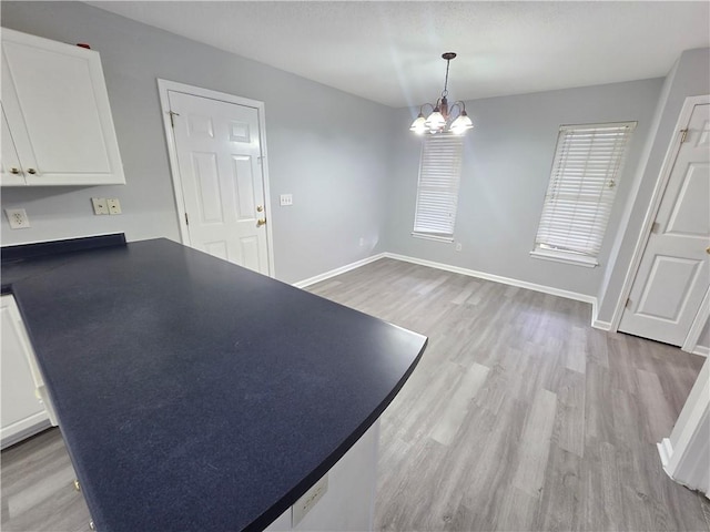 interior space featuring pendant lighting, light hardwood / wood-style floors, a chandelier, and white cabinetry