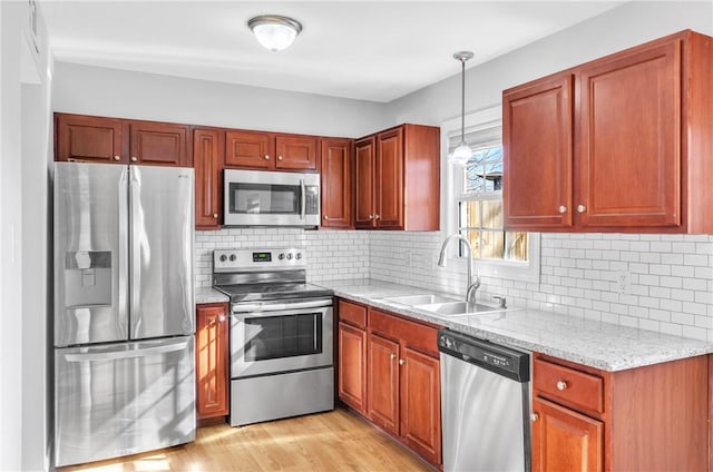 kitchen featuring stainless steel appliances, sink, decorative light fixtures, decorative backsplash, and light stone countertops