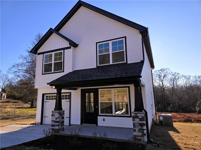 view of front facade with covered porch, central AC unit, and a garage