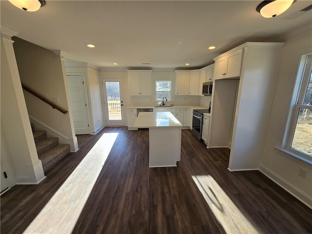 kitchen featuring appliances with stainless steel finishes, dark hardwood / wood-style floors, white cabinets, and a kitchen island