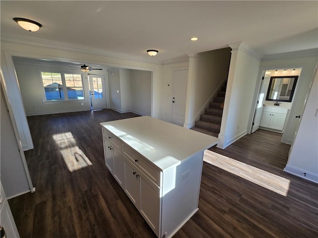 kitchen featuring a center island, dark hardwood / wood-style floors, white cabinetry, ornamental molding, and ceiling fan