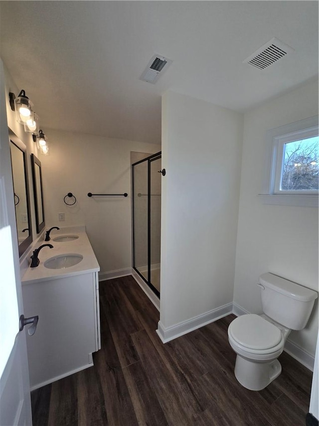 bathroom featuring vanity, hardwood / wood-style floors, a shower with shower door, and toilet