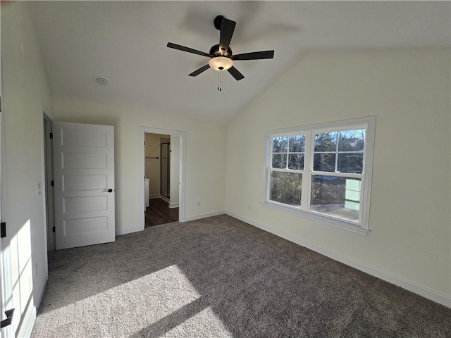 unfurnished bedroom with lofted ceiling, ensuite bath, dark colored carpet, and ceiling fan