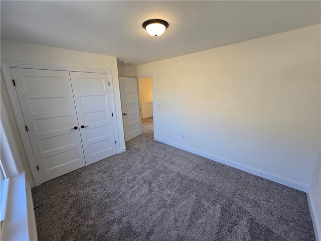 unfurnished bedroom with dark colored carpet and a closet