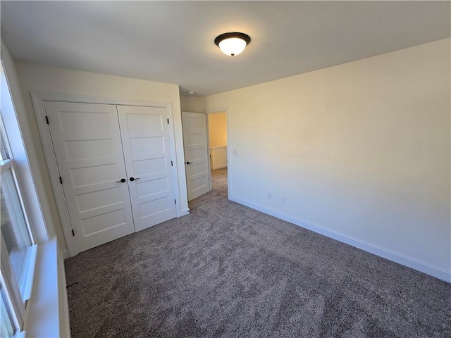 unfurnished bedroom with a closet and dark carpet