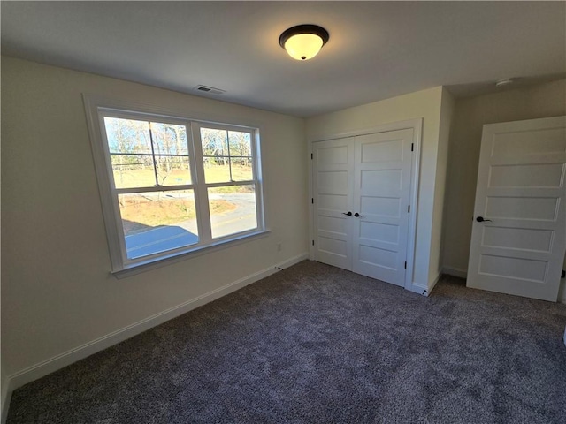 unfurnished bedroom featuring a closet and dark carpet