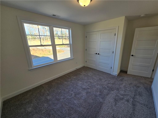 unfurnished bedroom with dark colored carpet and a closet