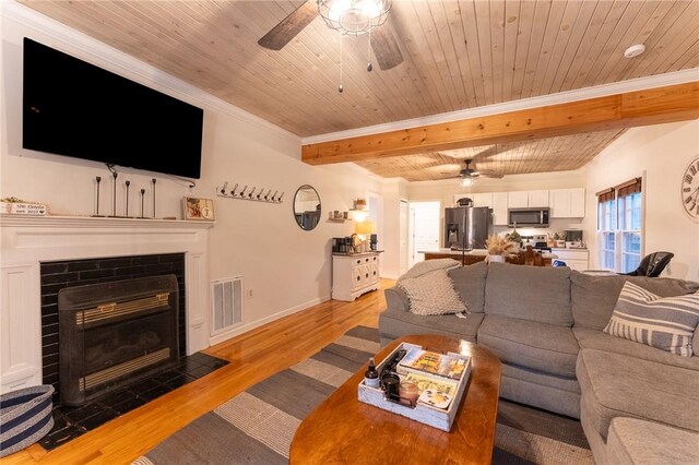 living room featuring beamed ceiling, wood ceiling, ceiling fan, light hardwood / wood-style floors, and crown molding