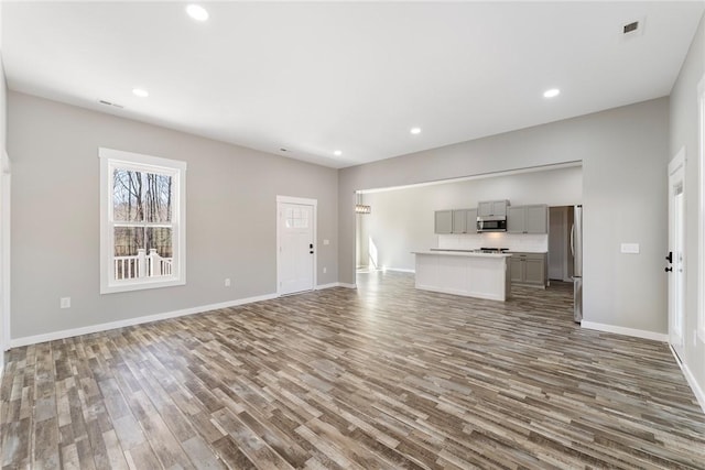 unfurnished living room with dark wood-style flooring, recessed lighting, and baseboards