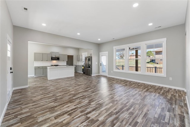 unfurnished living room featuring baseboards, dark wood-type flooring, and recessed lighting