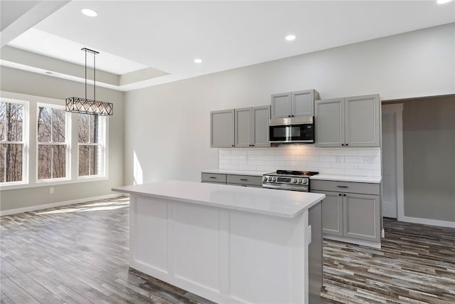 kitchen featuring stainless steel appliances, a center island, gray cabinets, and light countertops