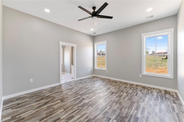 unfurnished room featuring plenty of natural light, visible vents, and wood finished floors