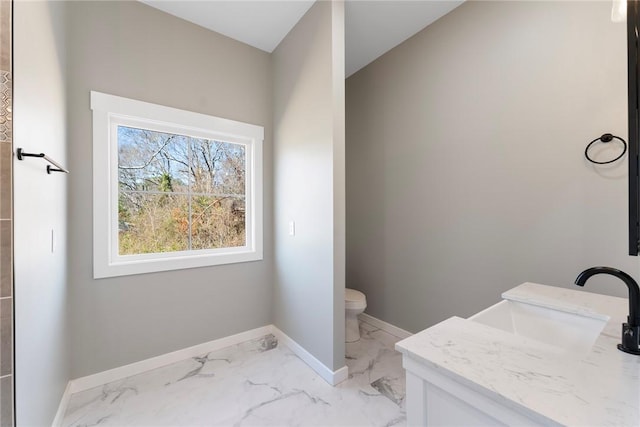 bathroom with marble finish floor, toilet, vanity, and baseboards