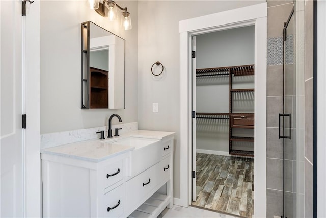 full bathroom featuring a tile shower, vanity, and wood finished floors