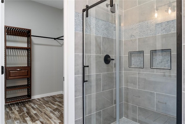 full bath with a stall shower, wood finished floors, and baseboards