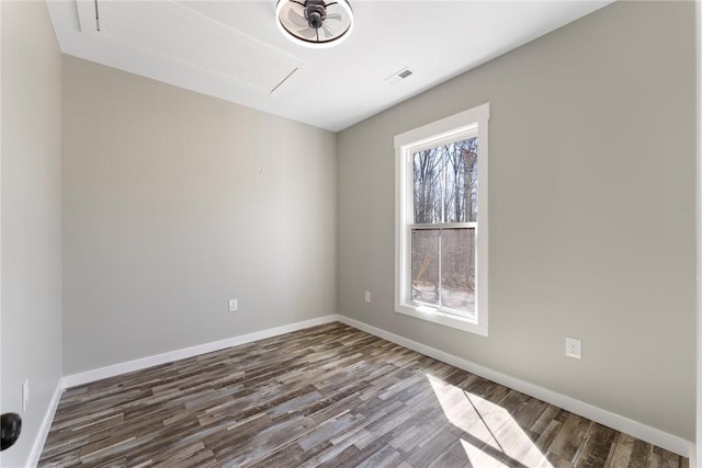 spare room featuring attic access, visible vents, baseboards, and wood finished floors