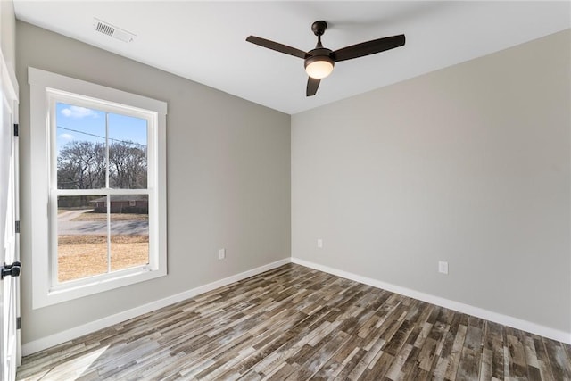 unfurnished room with plenty of natural light, wood finished floors, visible vents, and baseboards