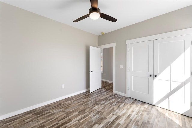 unfurnished bedroom with a ceiling fan, a closet, baseboards, and wood finished floors