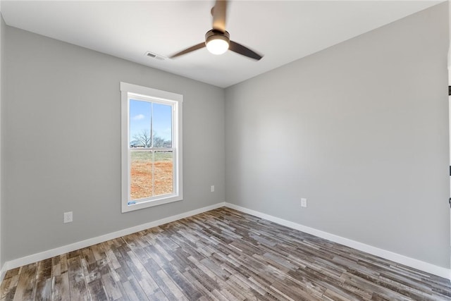 empty room featuring ceiling fan, wood finished floors, visible vents, and baseboards