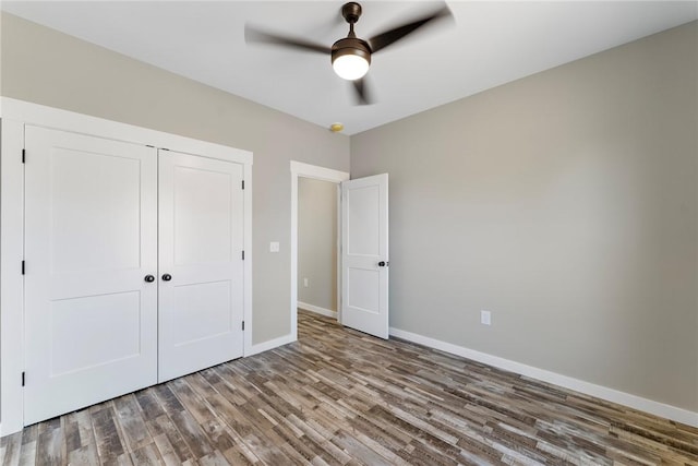 unfurnished bedroom featuring a ceiling fan, a closet, baseboards, and wood finished floors