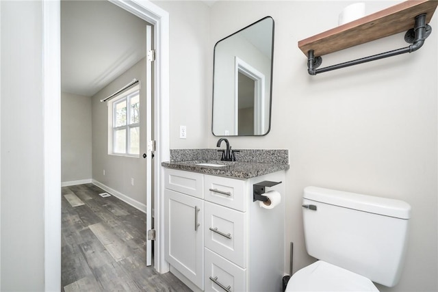 bathroom featuring toilet, hardwood / wood-style flooring, and vanity