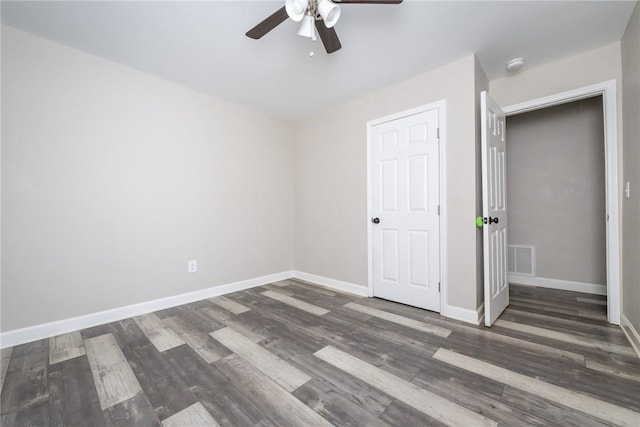 unfurnished bedroom with ceiling fan, dark wood-type flooring, and a closet