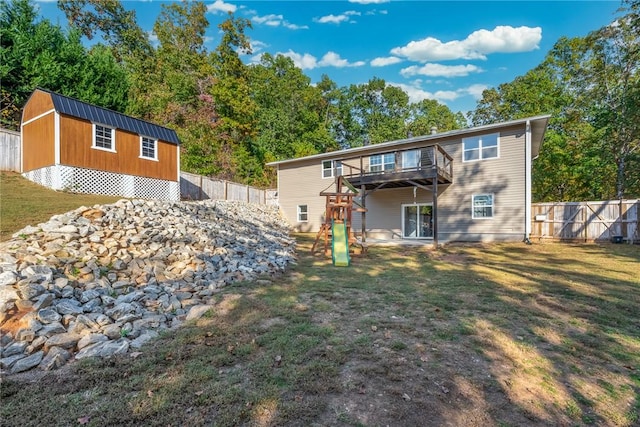 back of property with a playground, a lawn, and a storage unit