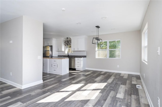 kitchen featuring butcher block countertops, refrigerator, decorative backsplash, stainless steel dishwasher, and white cabinets