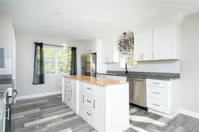 kitchen featuring wood counters, appliances with stainless steel finishes, white cabinets, and tasteful backsplash