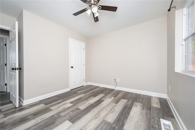 spare room with dark wood-type flooring and ceiling fan