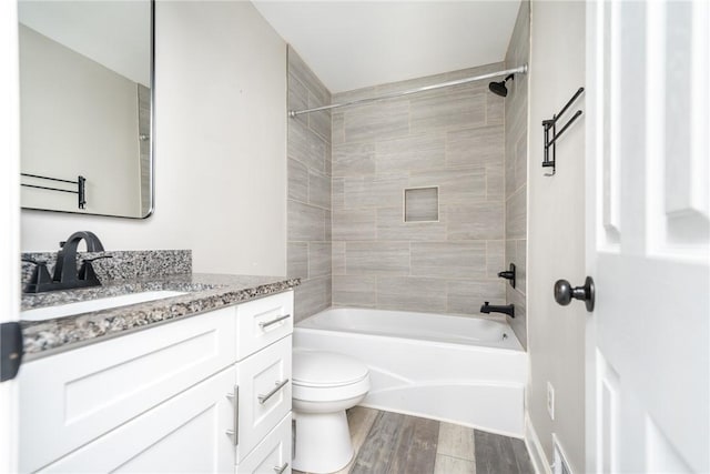 full bathroom with hardwood / wood-style flooring, tiled shower / bath combo, vanity, and toilet