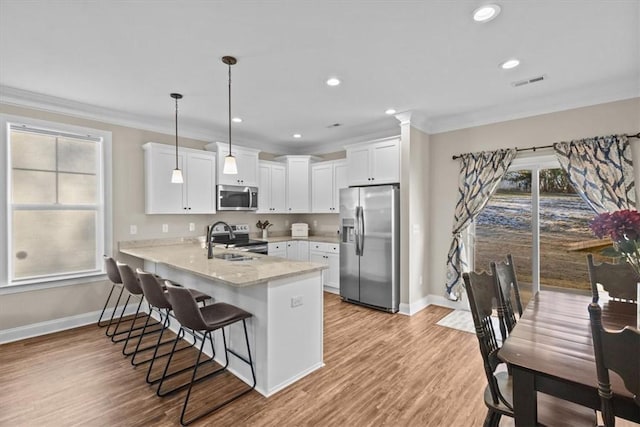 kitchen with kitchen peninsula, stainless steel appliances, a healthy amount of sunlight, hanging light fixtures, and sink