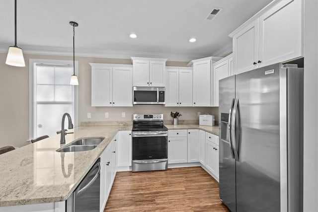 kitchen with sink, hanging light fixtures, appliances with stainless steel finishes, and white cabinets