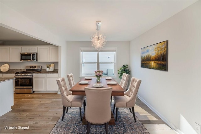 dining space with light hardwood / wood-style floors and a notable chandelier