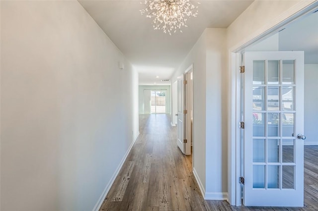 corridor with an inviting chandelier and hardwood / wood-style floors